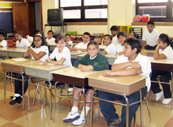 St. Philip Neri fifth-grade students Fernanda Gonzalez, from left, Christiana Mujica, Selena Monsivais and Carlos Martinez, in the front row, sit with classmates at old desks during the first day of school on Sept. 8. A major renovation took place at St. Philip Neri School in Indianapolis during the summer, and alumni are working to raise funds to help school officials purchase new furnishings for classrooms. (Submitted photo) 