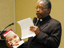 Father Kenneth Taylor, pastor of Holy Angels Parish in Indianapolis and director of the archdiocesan Office of Multicultural Ministry, discusses a story in Newsweek magazine, which addressed the question, “Is your baby racist?” He said people need to understand the reality of certain aspects of other cultures. (Photo by Mary Ann Wyand) 