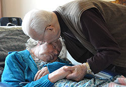 In this photo from June 2012, St. Augustine Home for the Aged resident Donald Bird of Indianapolis kisses his wife, Mary, in her room at the home operated by the Little Sisters of the Poor. A conference being held on Oct. 17 at the Archbishop Edward T. O’Meara Catholic Center in Indianapolis will address practical, legal and ethical issues that caregivers often face. (Criterion file photo)