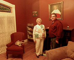 Sharon Gullett and Brent Freiberger visit the room in which Cardinal Joseph Ritter was born in the restored home at 1218 E. Elm St., New Albany. The two collaborated on a play about the cardinal’s life. A rare portrait of Ritter hangs over the mantel behind them. (Photo by Patricia Happel Cornwell)