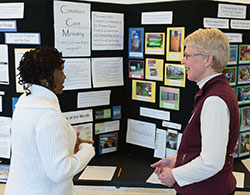 Sharon Horvath, right, a science teacher at St. Thomas Aquinas School in Indianapolis and a member of that parish’s Creation Care Ministry, shares ideas on March 28 with Domoni Rouse, who is interested in starting a green ministry at St. Rita Parish in Indianapolis. They were standing steps away from the chapel housed inside Marian University’s Evans Center for Health Sciences, which recently received LEED (Leadership in Energy and Environmental Design) Gold certification in recognition of its environmentally friendly design. All of the wood furniture in the chapel was constructed from the black walnut trees that once stood on the site. (Photo © Denis Ryan Kelly Jr.)
