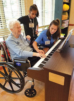 Student volunteers from St. Mary-of-the-Woods College help a resident play the piano at Providence Health Care, a ministry of the Sisters of Providence of Saint Mary-of-the-Woods. (Submitted photo)