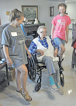 Catholic HEART Workcamp participants Felicia Samuels, left, and Sarah Pottorff, both of West Dundee, Ill., perform dance moves with a resident of the Little Sisters of the Poor’s St. Augustine Home for the Aged in Indianapolis on June 11. (Photo by Sean Gallagher)