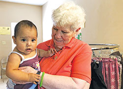 Franciscan Sister Marge Wissman holds a baby while volunteering in May at a shelter for asylum-seekers in Laredo, Texas. Sister Marge, two other Oldenburg Franciscan sisters and two lay women volunteered for two weeks at the shelter that primarily served those from Central American countries seeking asylum in the U.S. (Submitted photo)