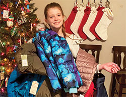 To celebrate her 12th birthday, Gracelyn Raelson asked her family, friends, classmates and fellow parish members to help her collect winter coats to distribute to people who needed one in southern Indiana and northern Kentucky. Her smile shows her joy about the 224 coats she collected. (Submitted photo)
