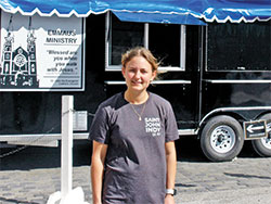 As the director of the Emmaus Ministry at St. John the Evangelist Parish in downtown Indianapolis that serves the homeless, Danielle Heitkamp stands in front of the parish’s new, deluxe food trailer that is key to that effort. (Photo by John Shaughnessy)