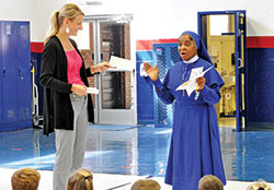 Daughters of Mary Mother of Mercy Sister Loretto Emenogu, archdiocesan mission educator for the Missionary Childhood Association (MCA), shows her astonishment as Tracy Jansen, principal of St. Mary of the Knobs School, presents her with a check for more than $16,000 the students raised to help children in need around the world. (Photo by Natalie Hoefer)