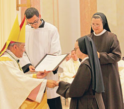 Franciscan Sister M. Evangeline Rutherford ritually receives a ring from Bishop Joseph N. Perry, at the time an auxiliary bishop of the Archdiocese of Chicago, during an Aug. 3 Mass at the chapel of St. Francis Convent in Mishawaka, Ind., during which she professed perpetual vows as a member of the Sisters of St. Francis of Perpetual Adoration. Assisting Bishop Perry is Nick Monin, a seminarian of the Diocese of Fort Wayne-South Bend. Looking on is Franciscan Sister Margaret Mary Mitchel, right, provincial superior of the Perpetual Adoration Franciscans based in Mishawaka. (Submitted photo) 