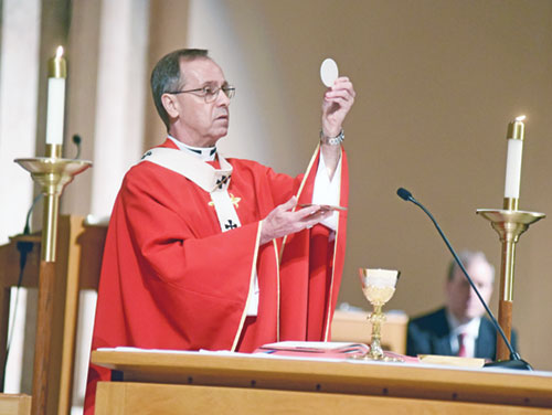 Archbishop Charles C. Thompson elevates the Eucharist during a Mass on June 29, 2020, in SS. Peter and Paul Cathedral in Indianapolis. In describing the impact of the Eucharist, the archbishop says, “It’s Jesus at work here in the lives of people.”  (File photo by Sean Gallagher)