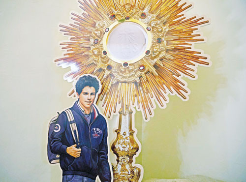 A display showing Blessed Carlo Acutis and a monstrance is seen near his tomb at the Church of Santa Maria Maggiore in Assisi, Italy, in this Oct. 3, 2020, file photo. The U.S. bishops chose Blessed Acutis as the patron of the first year of a three-year National Eucharistic Revival. The Italian teen, who is set to be canonized by Pope Francis, had a great love of the Eucharist and used his technology skills to build an online database of eucharistic miracles around the world. The National Eucharistic Congress will be held on July 17-21 in Indianapolis. (CNS photo/Paul Haring)