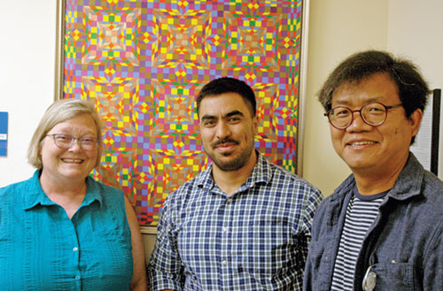 As the director of refugee services for the archdiocese’s Catholic Charities Indianapolis, Jessica Inabnitt uses her love of the Eucharist to guide her in helping refugees from around the world make a successful transition to life in the United States. Here, she poses for a photo with two members of her staff, Ahmad Ghaznawi, center, a job placement specialist who is a refugee from Afghanistan, and Anthony Khual, a cultural orientation specialist who is originally from Myanmar. (Photo by John Shaughnessy)