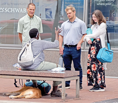 Russ Hoffman, left, Blake Brouilette of Christ in the City and Megan Ferguson speak with a homeless woman in Indianapolis on July 18. (Photo by Natalie Hoefer)